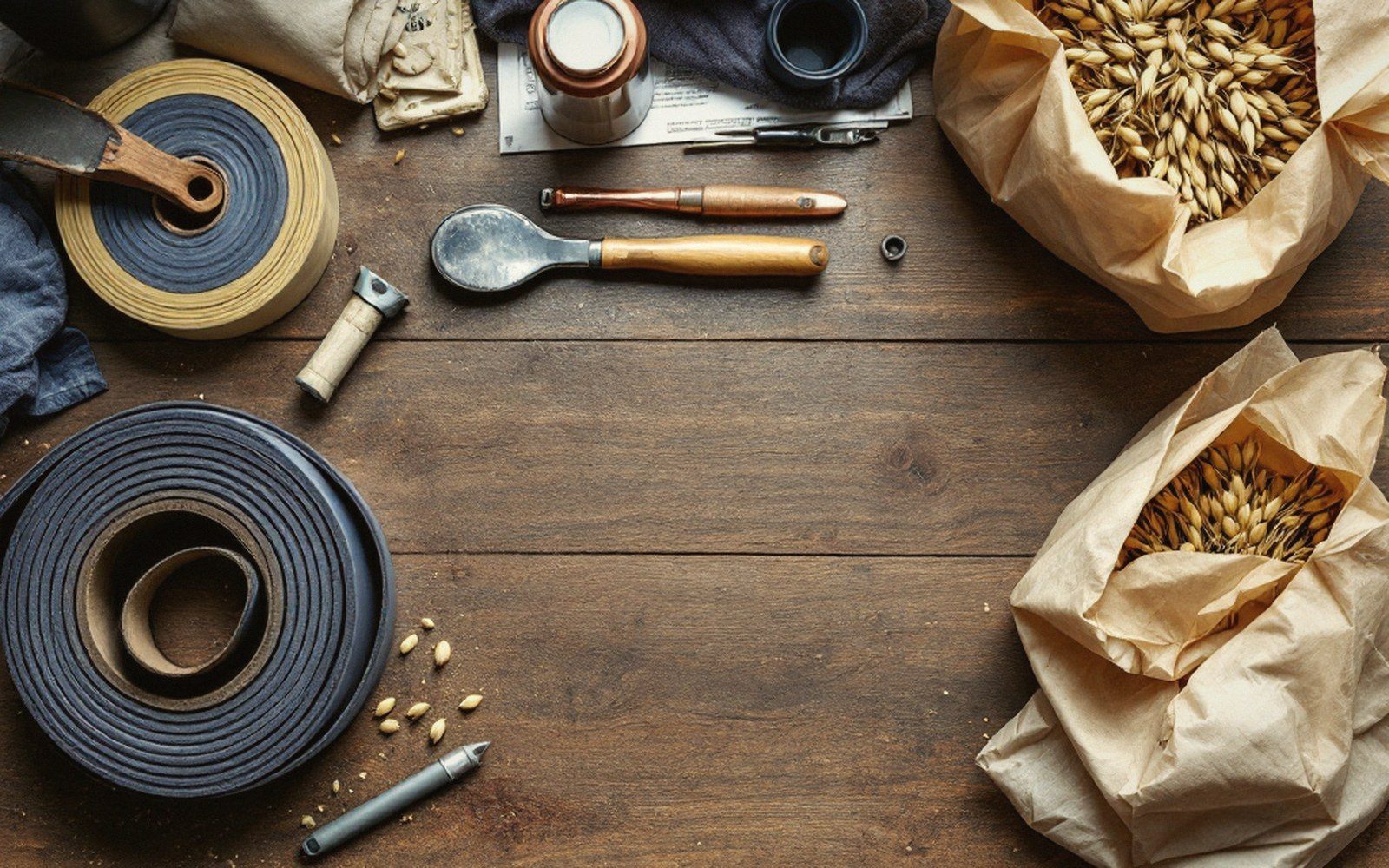 Rolled leather strips, scoops, and open sacks of grain arranged on a wooden table
